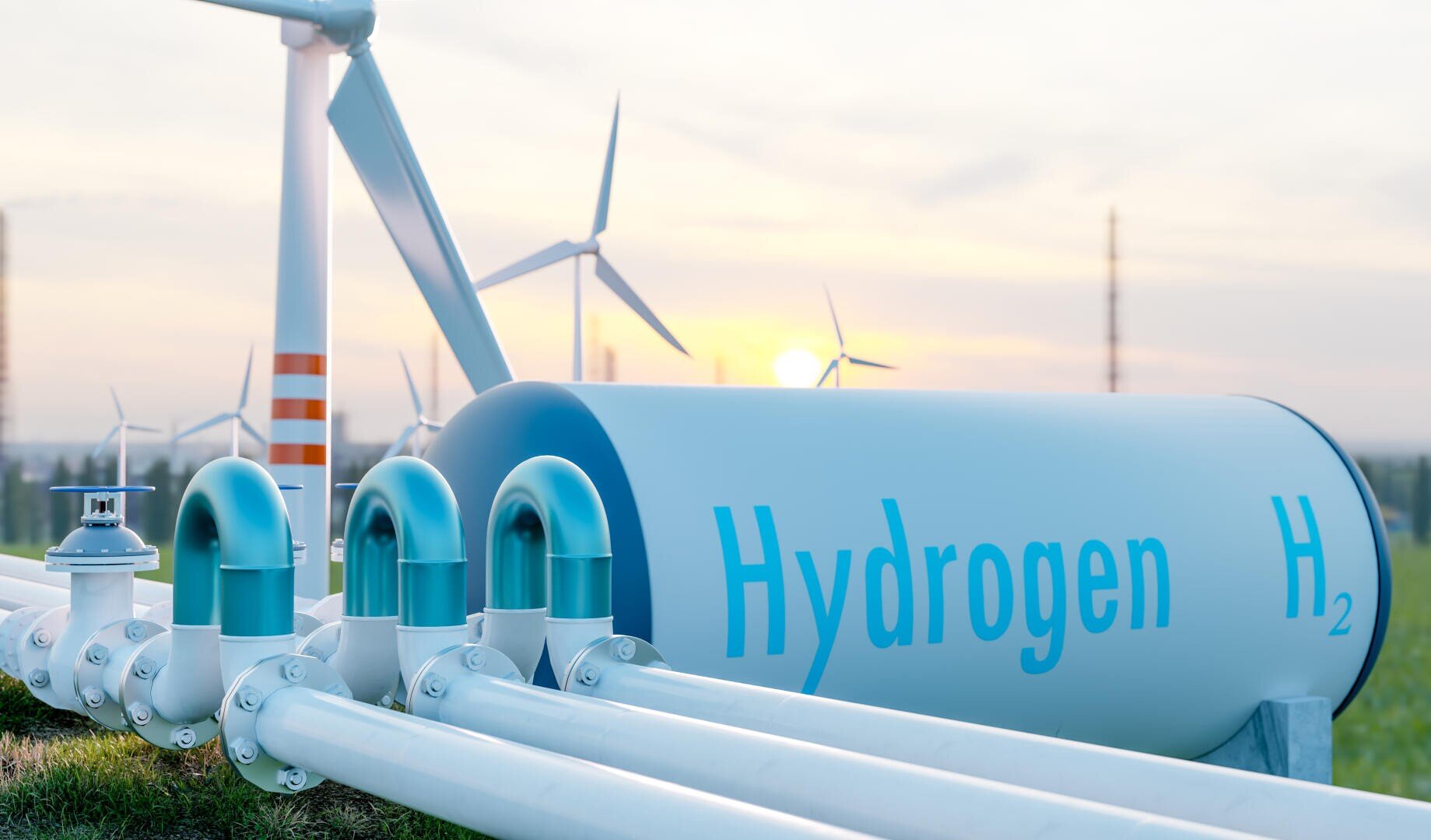 Ein großer Wasserstoffspeicher mit der Aufschrift Hydrogen H₂ ist an mehrere Rohre angeschlossen. Im Hintergrund sind Windturbinen zu sehen, die bei klarem Himmel für erneuerbare Energien und saubere Kraftstofftechnologie stehen.