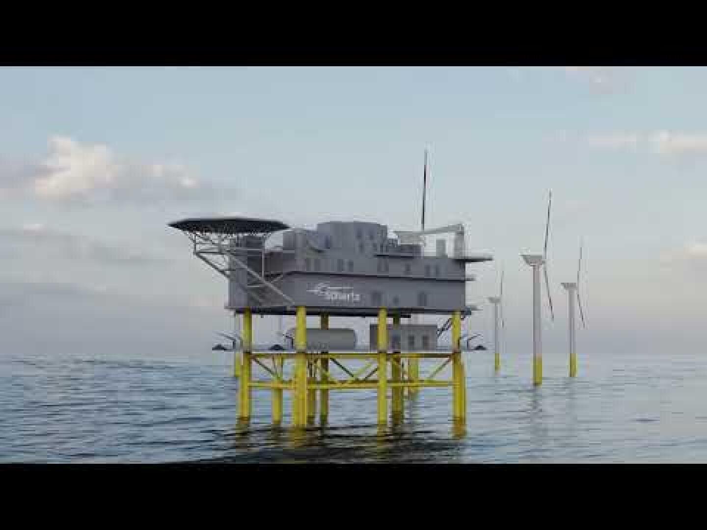 Eine Offshore-Plattform mit einem großen Gebäude ruht auf gelben Stützen im Meer. Im Hintergrund sind bei teilweise bewölktem Himmel Windkraftanlagen zu sehen.
