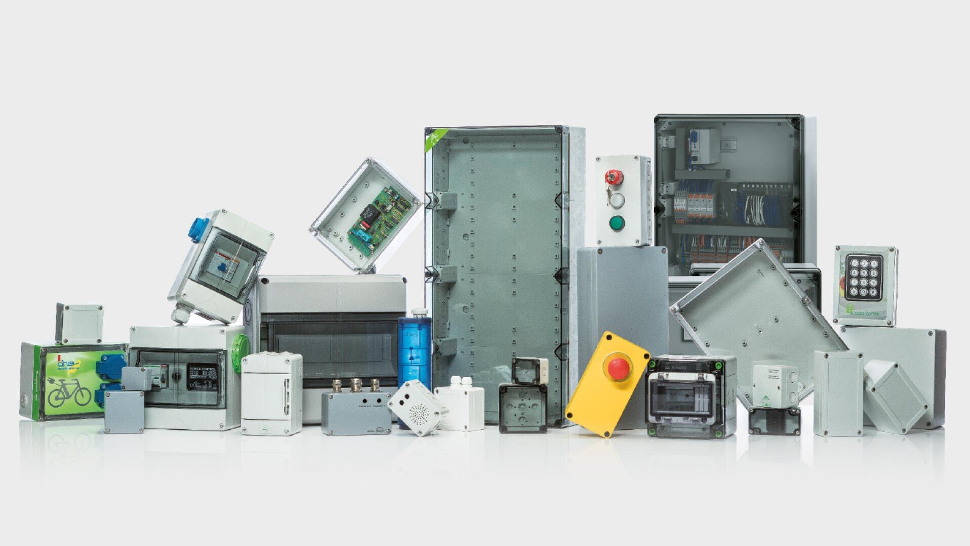 Eine Vielzahl von Schaltschränken und Verteilerkästen unterschiedlicher Größe und Form sind nebeneinander angeordnet, einige mit sichtbaren Kabeln, Tasten und elektronischen Bauteilen im Inneren.