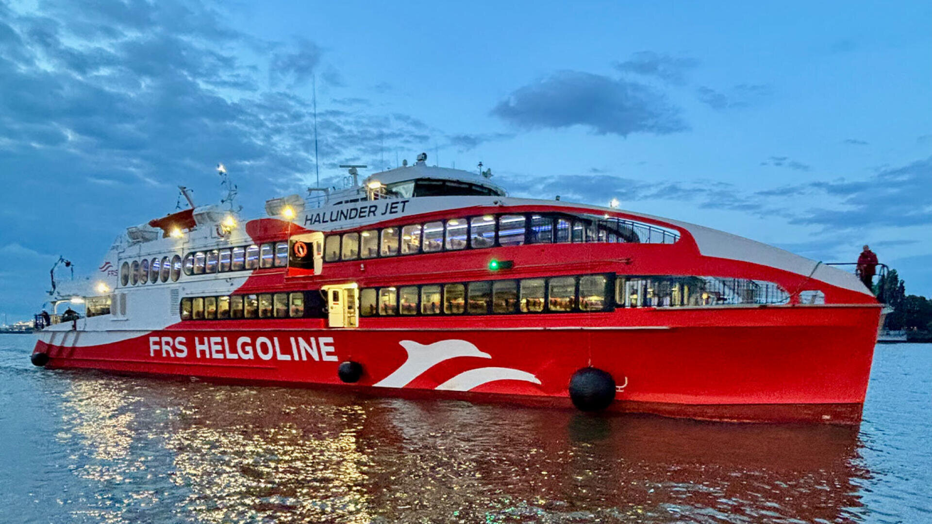 Die rot-weiße Passagierfähre Halunder Jet auf dem Wasser in der Abenddämmerung.