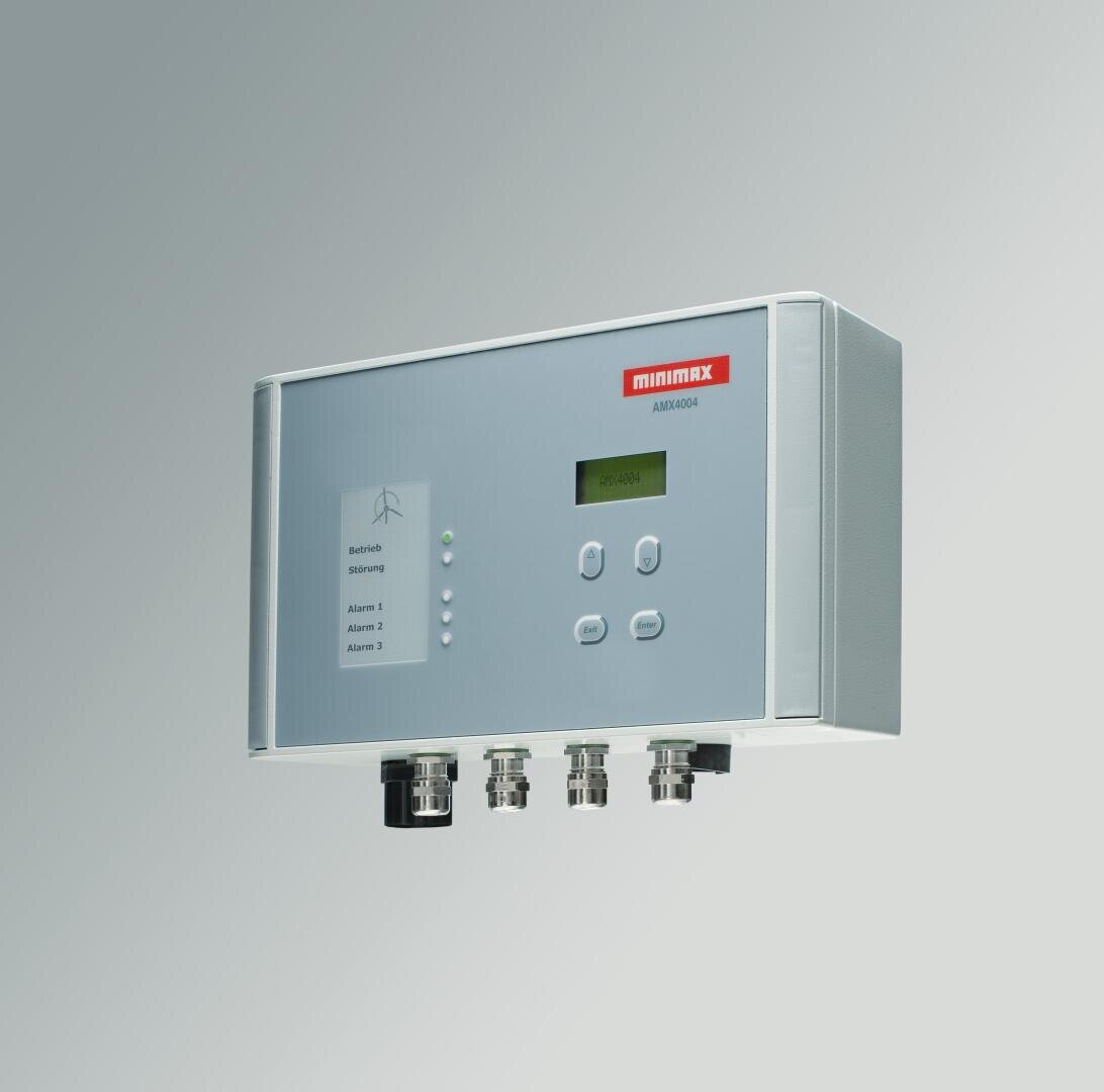 Ein rechteckiges elektronisches Bedienfeld mit der Aufschrift minimax AMI2000 mit einem kleinen Bildschirm, mehreren Tasten, Kontrollleuchten und vier Kabelanschlüssen an der Unterseite, montiert an einer hellgrauen Wand.