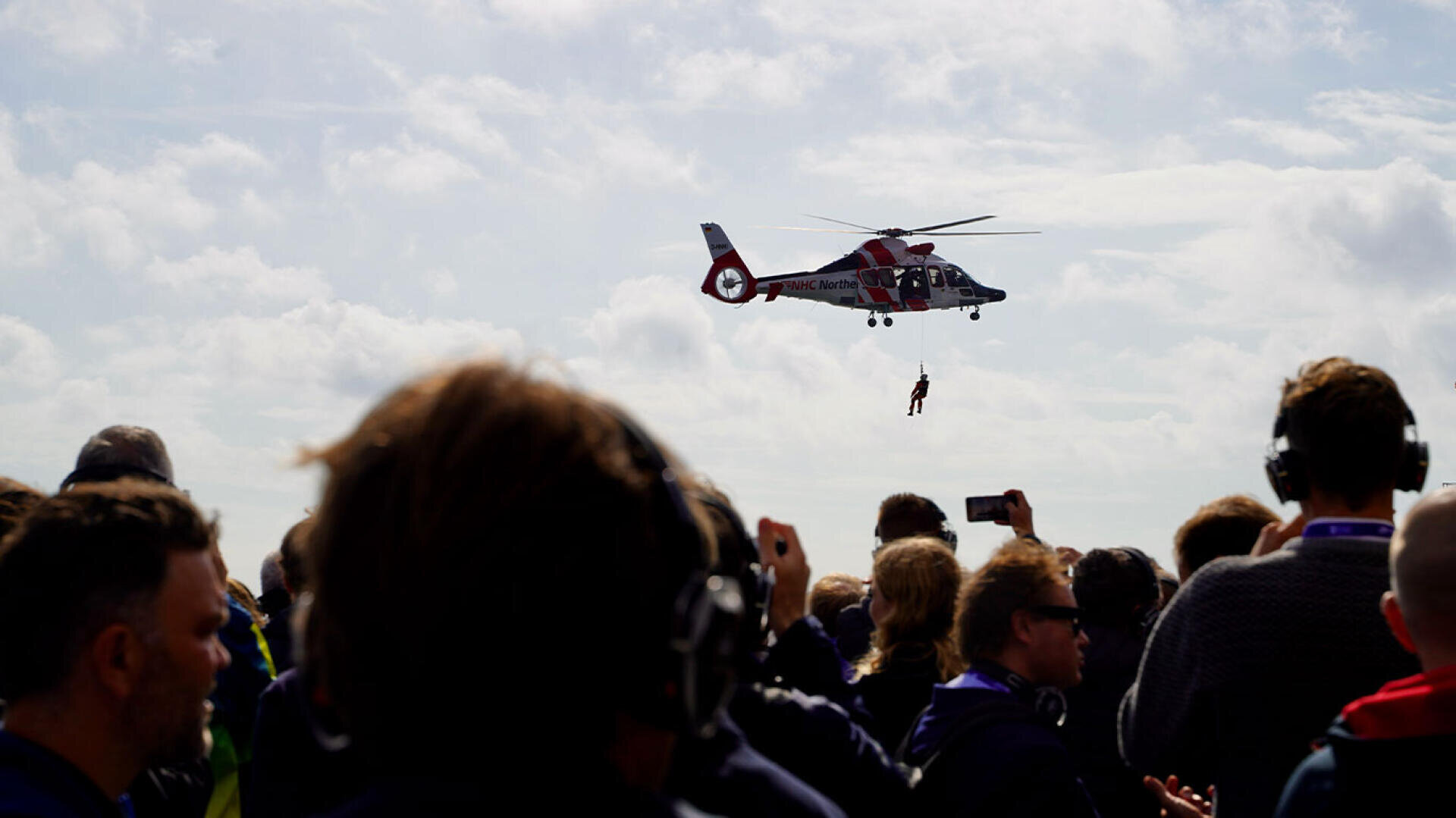Ein Rettungshubschrauber zieht eine Person an einem Seil über eine Menschenmenge hinweg.